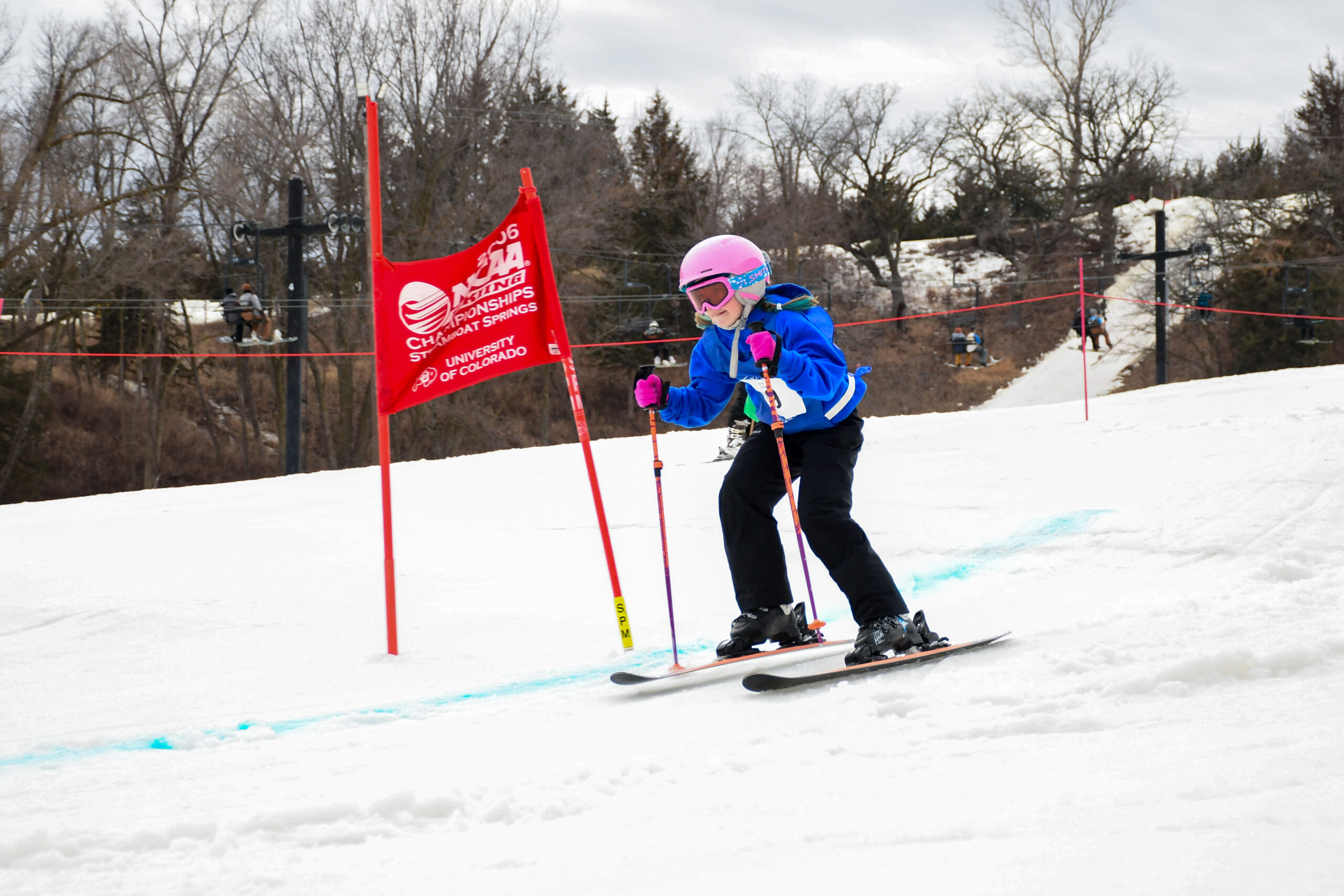 A young ski racer navigates past a red race gate.
