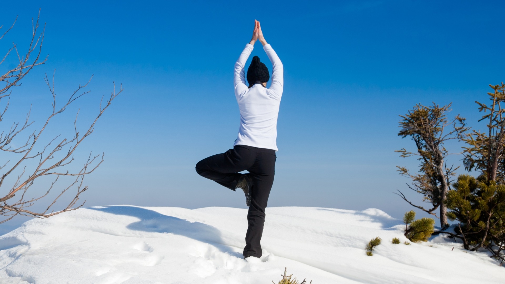 Person doing a standing yoga pose in the snow.